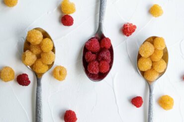 Gold berries and red raspberries on a spoon.