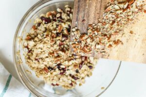 Granola being poured into a glass bowl.