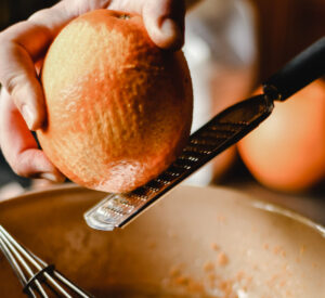 A woman zesting an orange.