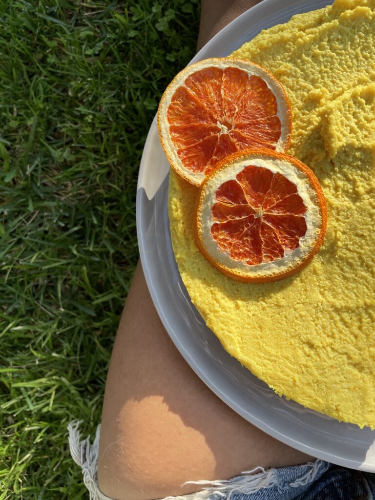 Vegan cheese cake garnished with two oranges.