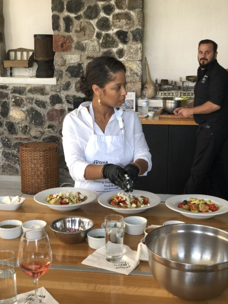 Nia Moore cooking with an apron on in Santorini.