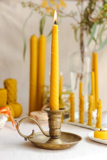 Yellow candlestick placed in a gold candle stick holder.