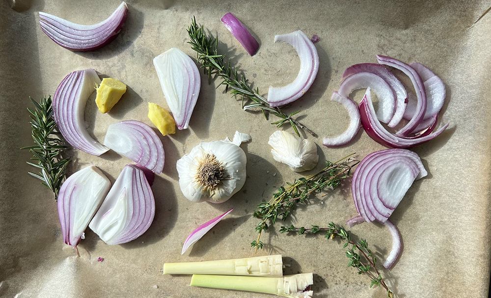 Lemongrass, onion, garlic, ginger, and herbs on a baking sheet.