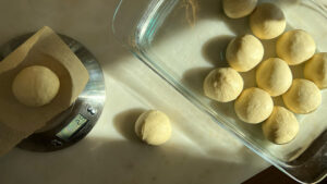 Balls of dough in a baking dish and a kitchen scale